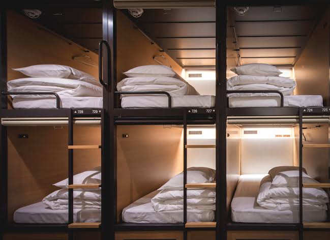 A corridor of sleeping berths and a shared lounge at Grids Tokyo Nihombashi East, Tokyo, Japan