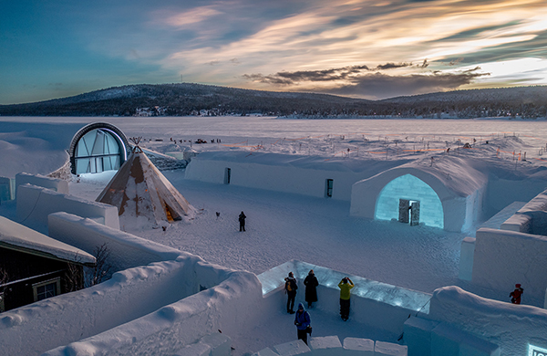 A winter lodge in a snowy clearing under low daylight